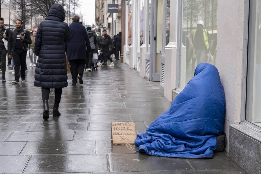 متسوقون يمرون بشخص بلا مأوى في شارع أكسفورد الصاخب في لندن