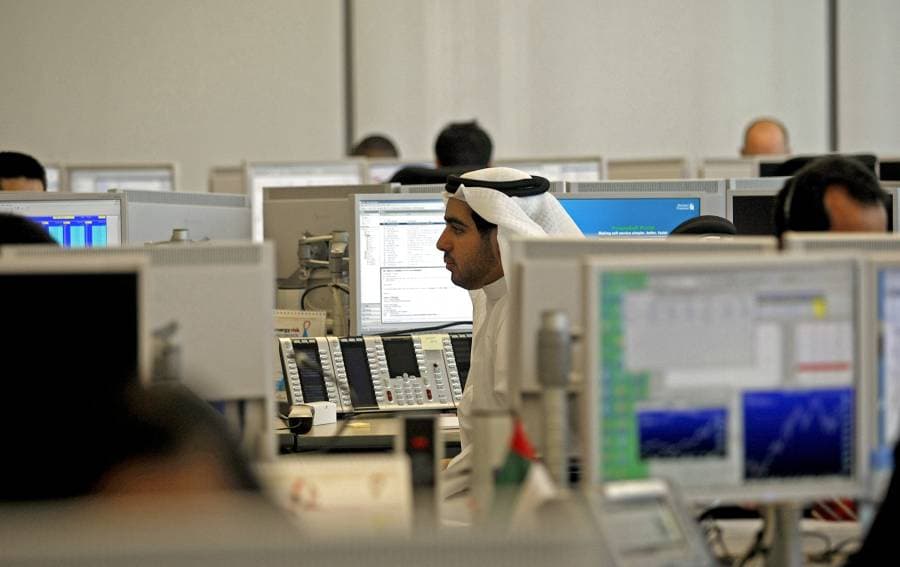 رجل يرتدي الزي الخليجي يجلس وسط قاعة كبيرة لأحد البنوك في دبي