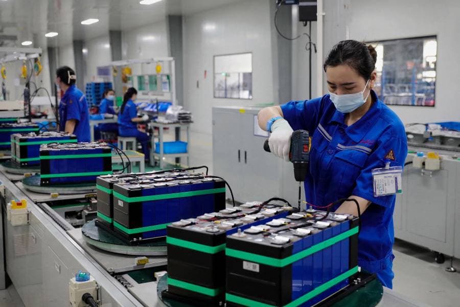 سيدة صينية تقف داخل مصنع لإنتاج البطاريات الكهربائية