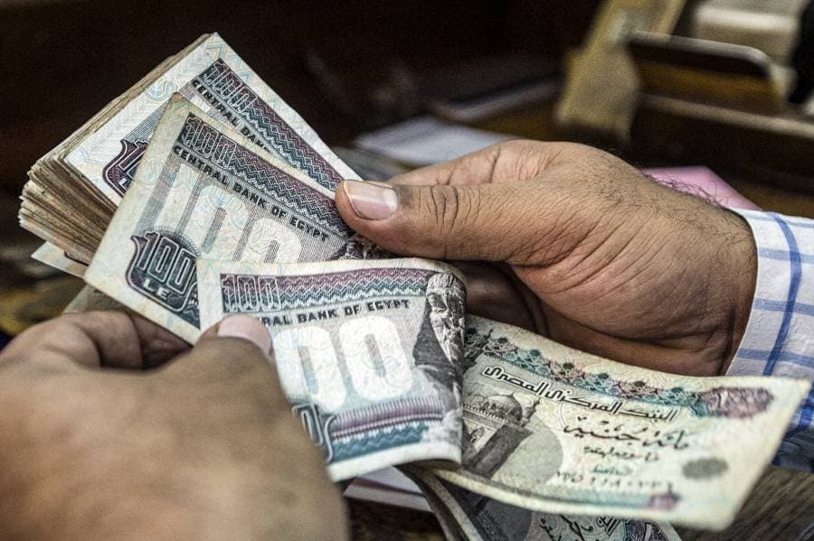 رجل يمسك مئات الجنيهات بالعملة المصرية