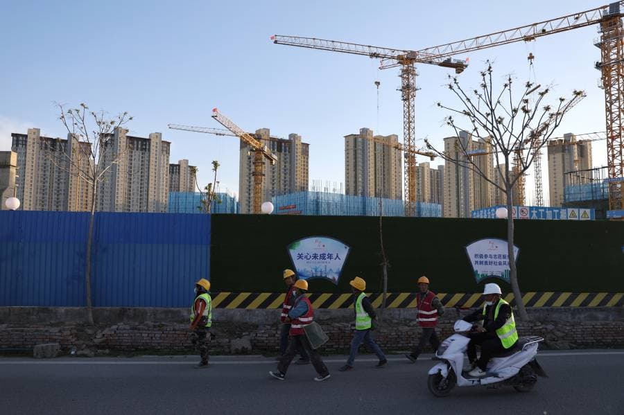عمال بناء يسيرون قرب موقع بناء في بكين