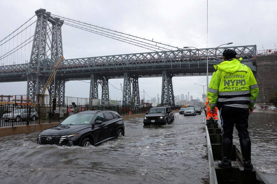 رجل شرطة نيويورك يقف وسط السيارات الغارقة في الفيضانات
