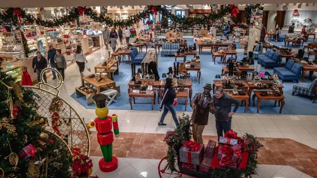 متسوقون يمرون بالقرب من عرض شجرة عيد الميلاد في متجر في ديسمبر 2023