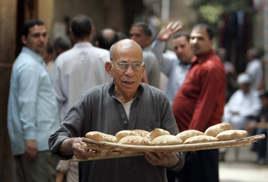 رجل مصري يحمل الخبز في القاهرة وآمال بعدم ارتفاع أسعار الغذاء