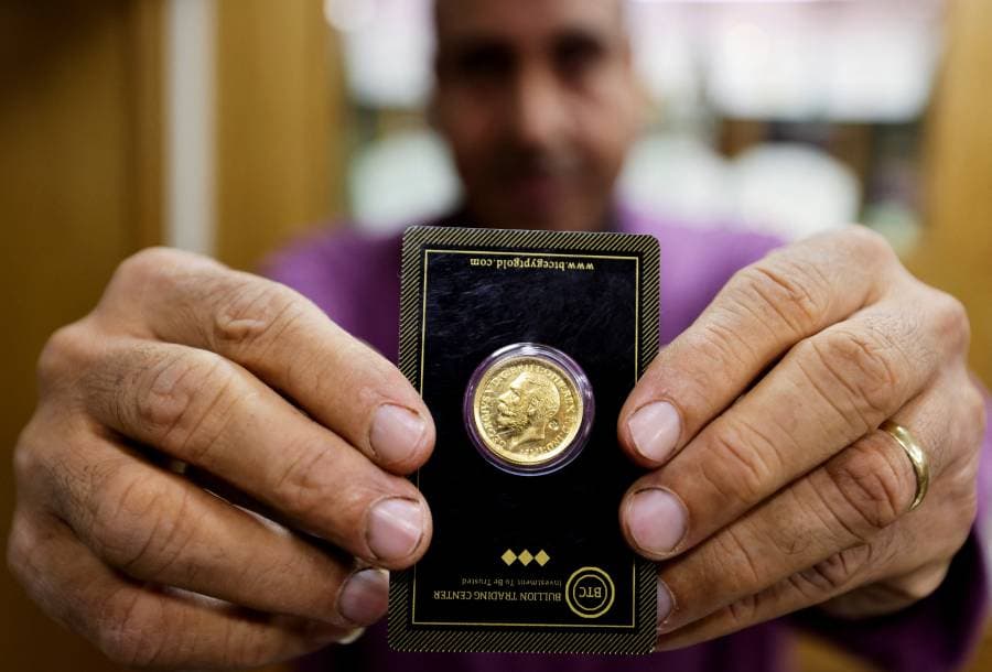 بائع ذهب يحمل عملة ذهبية داخل متجر بمنطقة سوق الذهب في القاهرة