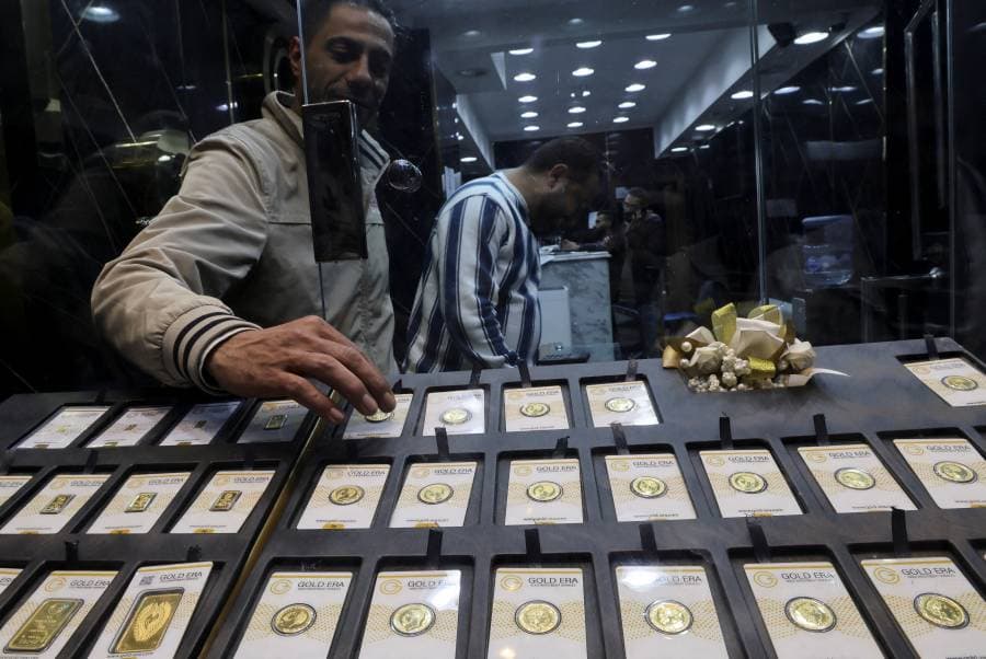 بائع في محل ذهب يقف أمام عشرات العملات الذهبية في متجر بمصر