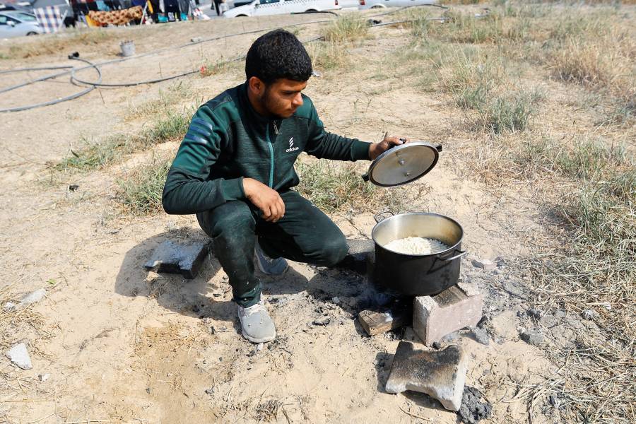 فلسطيني فر من منزله وسط الغارات الإسرائيلية، يعد الطعام بينما كان يحتمي في مركز تديره الأمم المتحدة